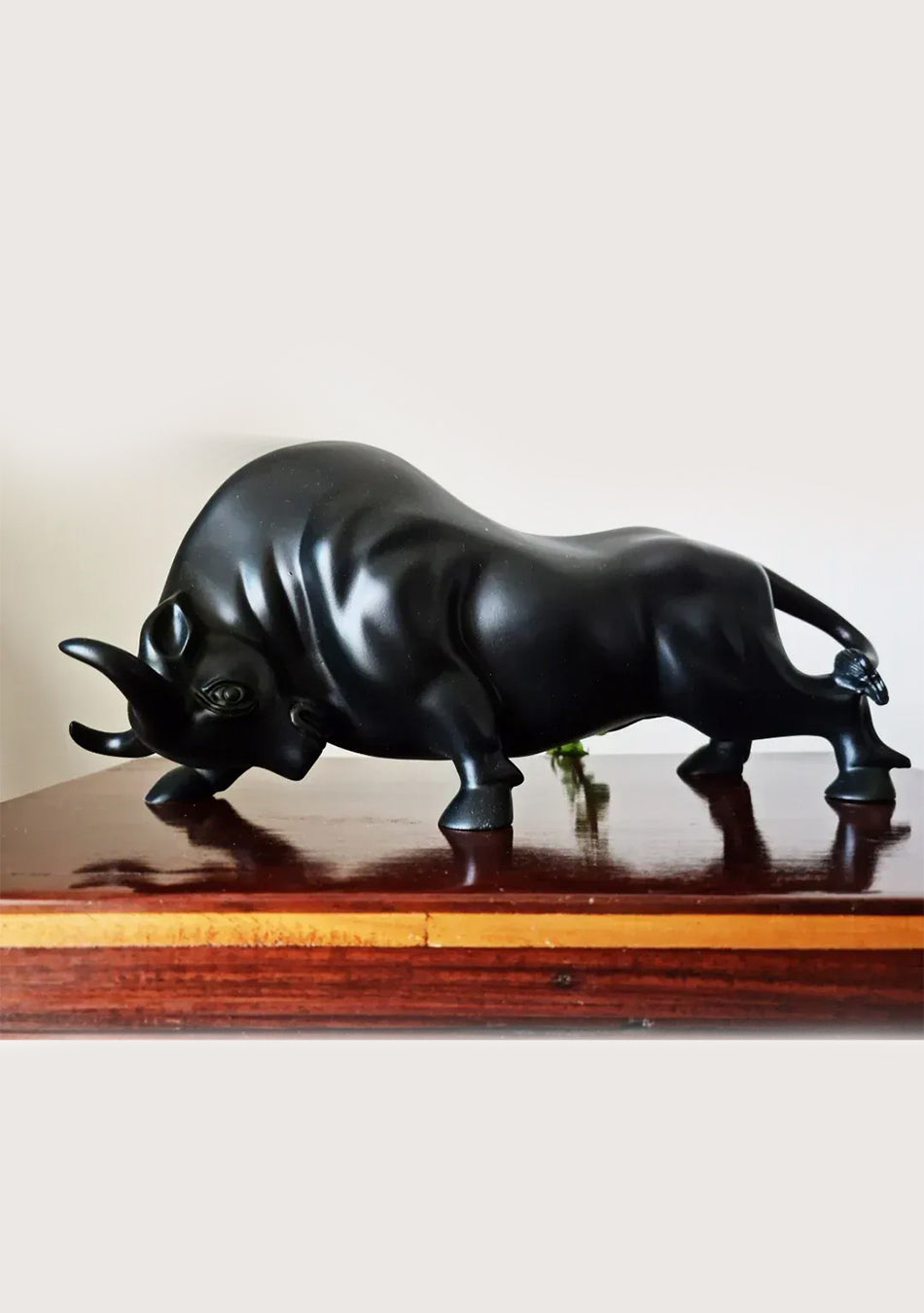 Aravalii Charging Bull Figurine in grey antique resin finish styled as an auspicious Vastu accent on a dark wood office desk